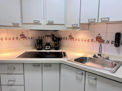 a kitchen with white cabinets and a sink at Vista al Mar in Caraballeda