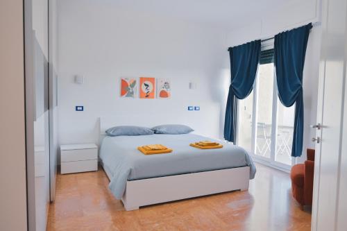 1 dormitorio blanco con 1 cama con cortinas azules en Artemisia, en Sestri Levante