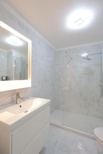 une salle de bain blanche avec un lavabo et une douche dans l'établissement Roses des Mers - Apt Standing 2 Prs - Clim - Parking, à Antibes