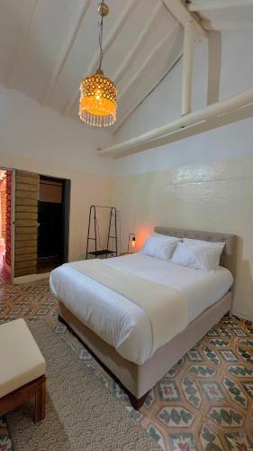 a bedroom with a large white bed and a chandelier at Hotel Casa Amalia in Villa de Leyva