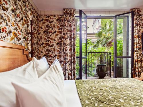 a bedroom with a bed and a large window at Hôtel Eldorado Paris in Paris