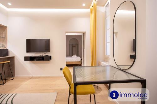 une salle à manger avec une table en verre et un miroir dans l'établissement Air-conditioned apartment in Old Nice, à Nice