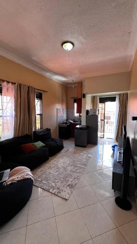 a large living room with a couch and a kitchen at Comfy Square in Kampala