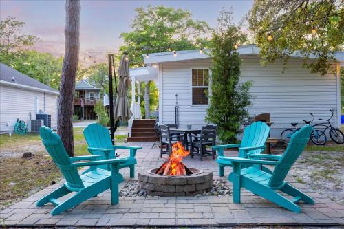 three chairs and a fire pit in front of a house at Modern Oak Island Escape 1 Mile to Long Beach! in Oak Island