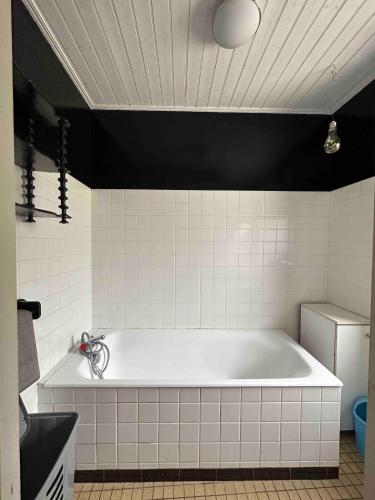 La salle de bains est pourvue d'une baignoire et de carrelage noir et blanc. dans l'établissement résidence agréable proche de la mer, à Saint-Gervais