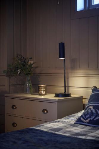 a bedroom with a bed and a lamp on a dresser at Beitostølen! Midt i sentrum! Ski in ski out! Badstue-Massasjedusj-Steamdusj in Beitostøl