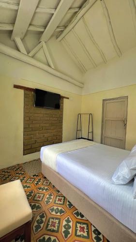 a bedroom with two beds and a flat screen tv at Hotel Casa Amalia in Villa de Leyva