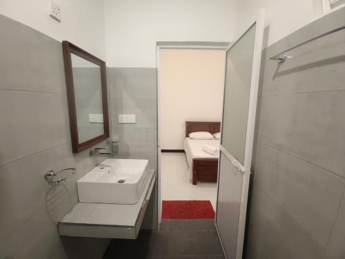 ein Badezimmer mit Waschbecken und Spiegel und einem Bett in der Unterkunft Chandra Holiday Home in Dikwella