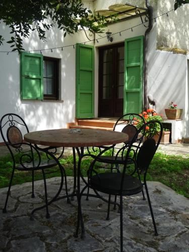 a table and chairs in front of a house with green shutters at Camera D'Ambra in Campiglia Marittima