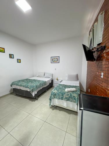 a room with two beds and a tv in it at Pousada Terra Do Sol in Arraial do Cabo