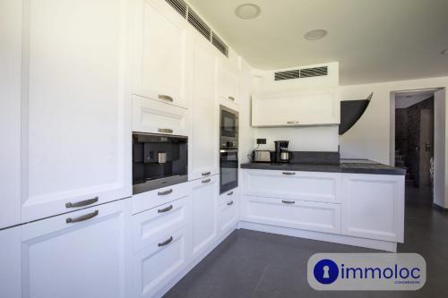 a white kitchen with white cabinets and appliances at Air-conditioned villa with pool and garden in Mandelieu-la-Napoule