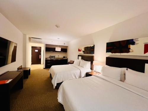 a hotel room with two beds and a television at Holiday Inn Guadalajara Patria-Universidad by IHG in Guadalajara