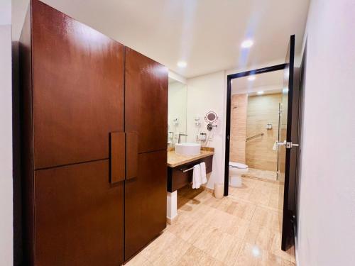 a bathroom with a wooden door with a sink and a toilet at Holiday Inn Guadalajara Patria-Universidad by IHG in Guadalajara