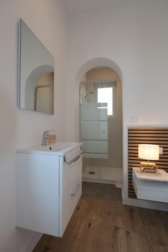une salle de bain blanche avec un lavabo et un miroir dans l'établissement Cosy Muguets - Luxury Apartment for 6 People with Sea View, à Vallauris