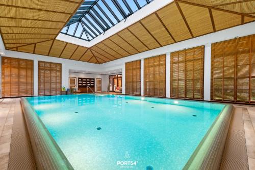 a large swimming pool in a building with a skylight at Maybach Suite Westerland auf Sylt in Westerland