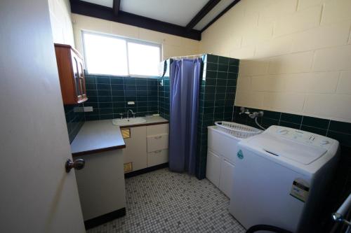 a small bathroom with a washing machine and a sink at Bella Beach 575-77 Straight St Hat Head in Hat Head