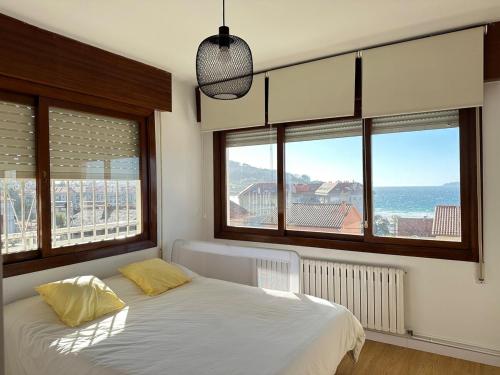 Un dormitorio con una cama con vista al mar. en Patos Sunset Beach House, en Nigrán