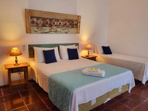 two beds in a room with two tables and two lamps at Pousada Do Ó in Tiradentes
