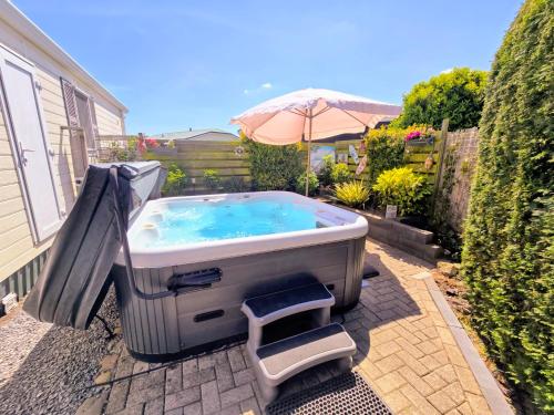 De Poort van Zeeland aan het water met jacuzzi في سينت انالاند: حوض استحمام ساخن في الفناء الخلفي مع مظلة