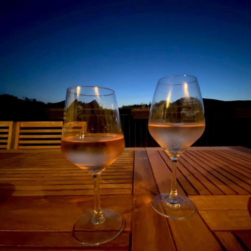 two glasses of white wine sitting on a wooden table at Mas de Cala, gîtes détente au Pic Saint Loup in Saint-Mathieu-de-Tréviers