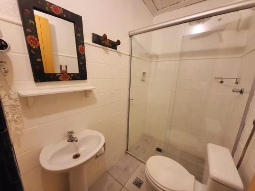 a bathroom with a toilet and a glass shower at Pousada Do Ó in Tiradentes