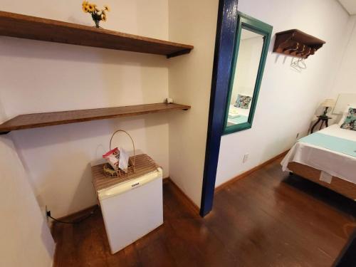 a room with a bed and a table and a mirror at Pousada Do Ó in Tiradentes