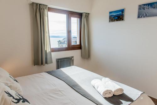 a bedroom with a bed and a window with towels at Del Lago Sky Hotel in San Carlos de Bariloche