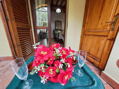 - une table avec des fleurs rouges et des verres à vin dans l'établissement Max and Lea's House, à Riparbella
