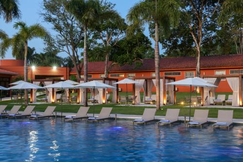 a pool with chairs and umbrellas next to a resort at Sanma Hotel in Foz do Iguaçu