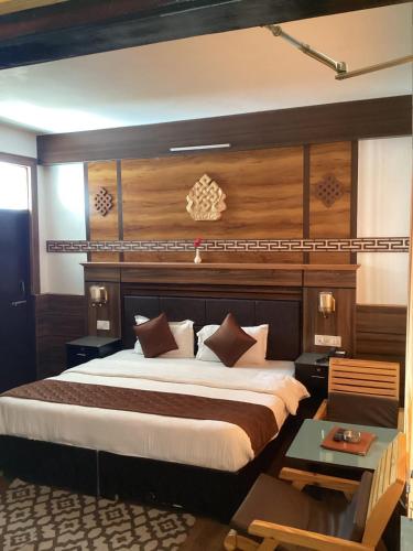 a bedroom with a large bed with a wooden headboard at Hotel Blue Pine in Kyelang
