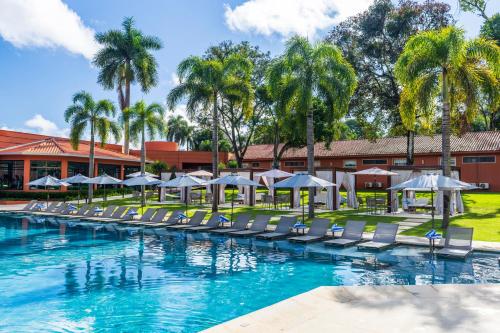 a swimming pool with lounge chairs and umbrellas at Sanma Hotel in Foz do Iguaçu