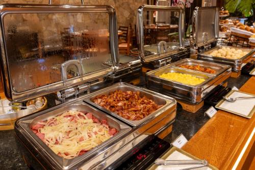 a buffet line with trays of different types of food at Sanma Hotel in Foz do Iguaçu