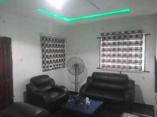 a living room with two chairs and a green light at 2-Bedroom Tradebybata Apartments around FUNAAB Abeokuta in Abeokuta