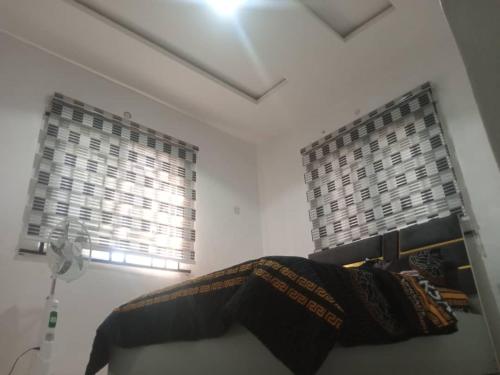 a room with two windows and a bed in it at 2-Bedroom Tradebybata Apartments around FUNAAB Abeokuta in Abeokuta