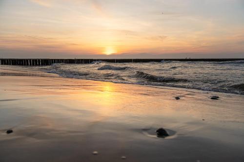 a sunset on a beach with the ocean at Aquapark Health Resort & Medical SPA Panorama Morska All Inclusive in Jarosławiec