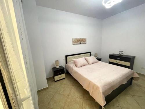 a bedroom with a bed with two night stands and two tables at Ermes Center Apartment in Elbasan