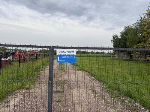 a fence with a sign on it in a field at Uroczy duży dom nad jeziorem z prywatną przystanią in Steklinek