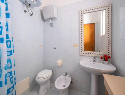 a bathroom with a toilet and a sink and a mirror at Charming Italian Villa in Torre Castiglione in Torre Lapillo