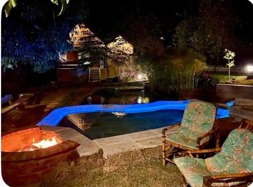 a backyard with a pool and two chairs and a fire pit at Chácara Namorada do Sol - Pousada e Camping in Guaxupé