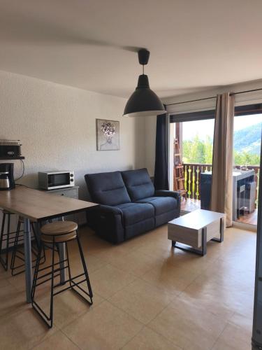 un salon avec un canapé bleu et une table dans l'établissement Location vacances Barcelonette, à Barcelonnette