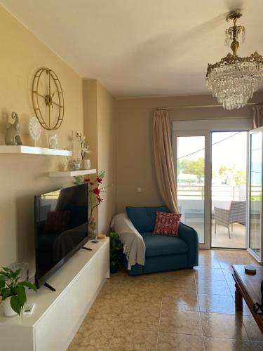 a living room with a blue couch and a flat screen tv at MARIA cozy apartments in Sfakaki