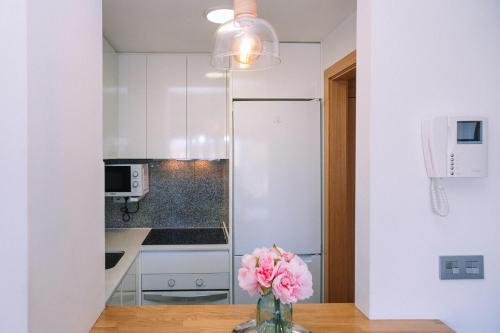a vase of pink flowers on a table in a kitchen at Piscina y garaje cerca del centro by CABANA Rentals in Vigo