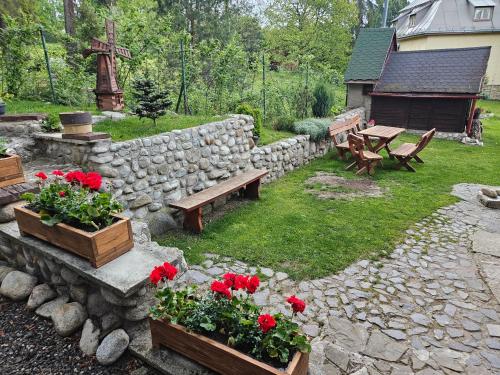 a garden with a stone wall and benches and red flowers at Vila Kamila in Tatranska Strba
