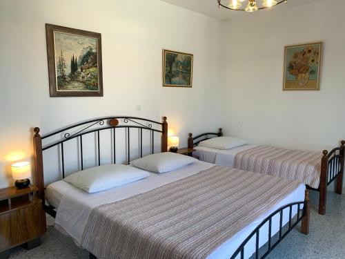 two beds in a bedroom with two lamps and paintings at Green Apartment in Sreser