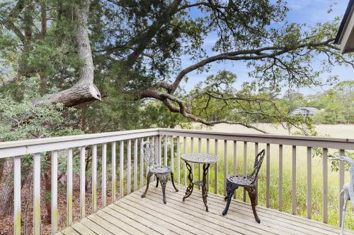 2 Stühle und ein Tisch auf einer Terrasse mit einem Baum in der Unterkunft 1237 Creekwatch in Seabrook Island