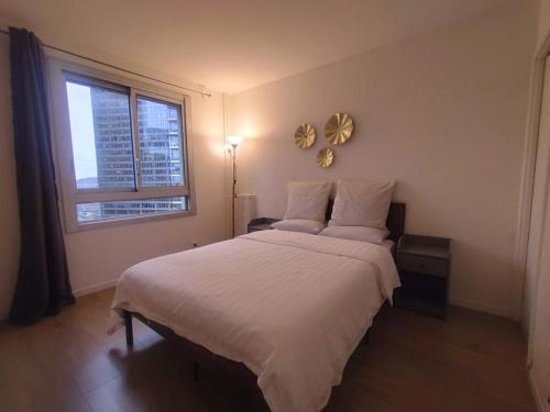 une chambre avec un grand lit blanc avec une fenêtre dans l'établissement 4 bedrooms, La Défense, 5 min walk to metro, à Courbevoie