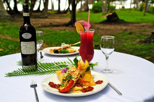 a table with two plates of food and a bottle of wine at Ankobra Beach Resort in Axim