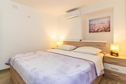 a bedroom with a large bed and two lamps at Anabella in Martinšćica