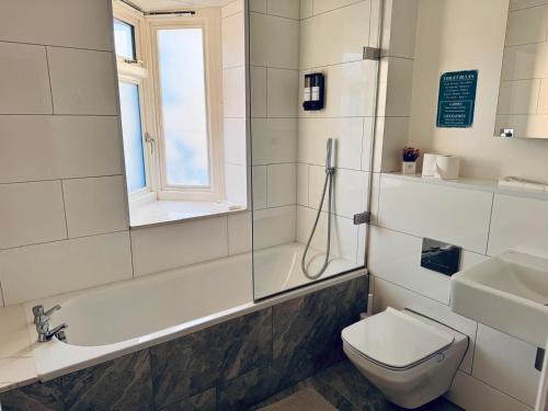 a bathroom with a tub and a toilet and a sink at 40th Avenue Guest House in Mill Hill