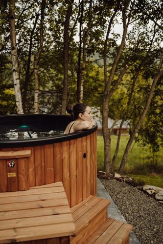 a woman is sitting in a hot tub at Czill-Lokum- klimatyczna chata w Beskidach z balią i sauną in Maków Podhalański